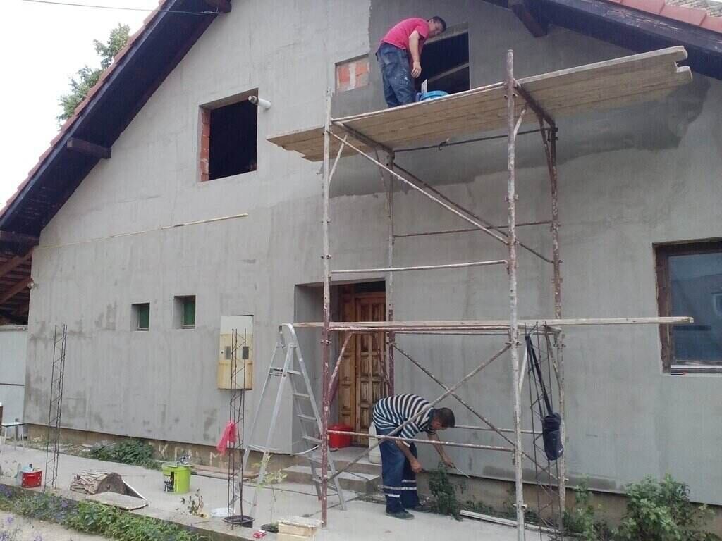 Radnici na skeli rade fasadu na kući